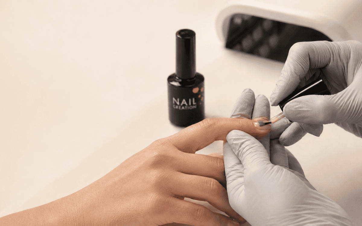 Professional nail technician applying gel carefully without touching the surrounding skin