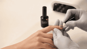 Professional nail technician applying gel carefully without touching the surrounding skin